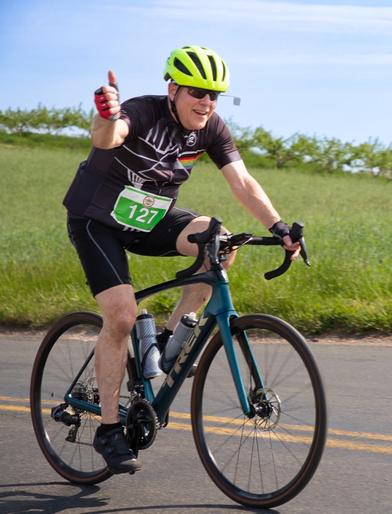 Rider giving a thumbs up while cycling on a country road