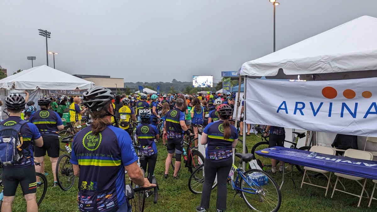 A large crowd of riders gathered at the starting line under a stormy sky